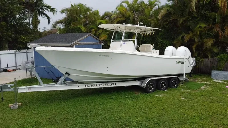 Slide: The Image of 2011 Mako 284 CC boat on trailer, parked on grass near palm trees. - 4
