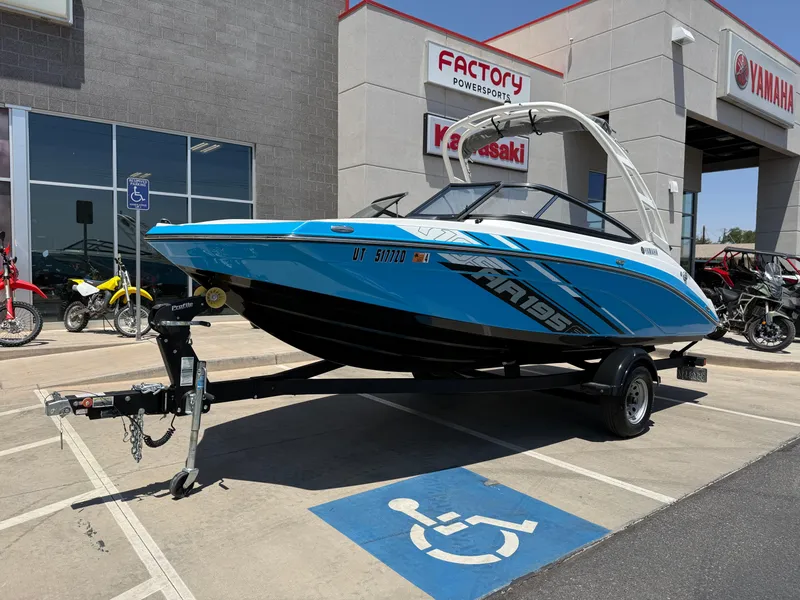 Slide: The Image of 2021 Yamaha AR195 boat on trailer outside dealership, featuring sleek blue design. - 2