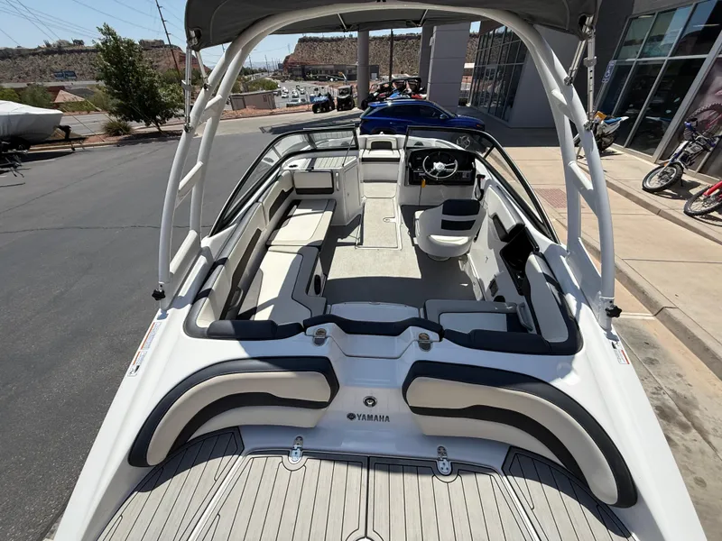 Slide: The Image of 2021 Yamaha Boats AR195 interior view, showcasing seating and steering area in a parking lot. - 40