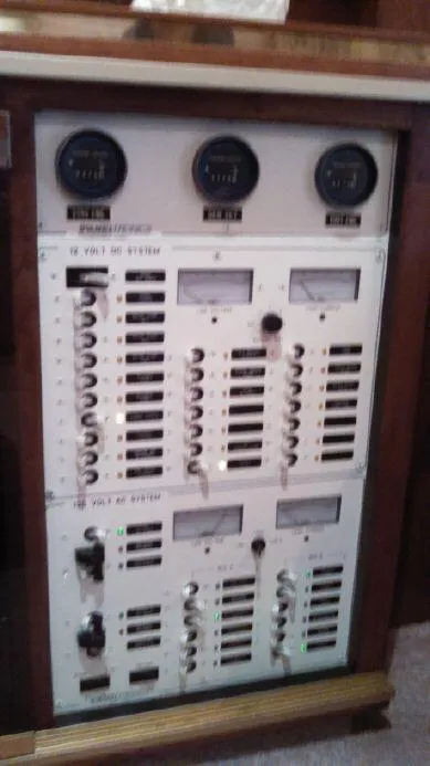 Slide: The Image of 1973 Trojan F-32 electrical panel with gauges and switches for 12V and AC systems. - 11
