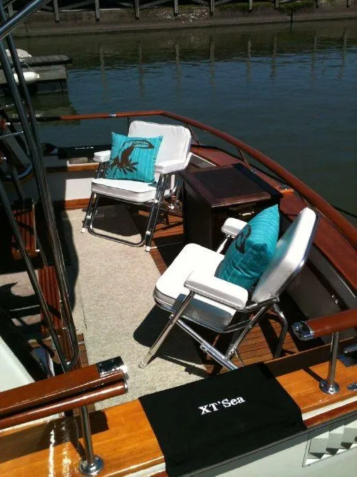 Slide: The Image of 1973 Trojan F-32 boat deck with chairs, cushions, and "XT' Sea" mat by the water. - 5