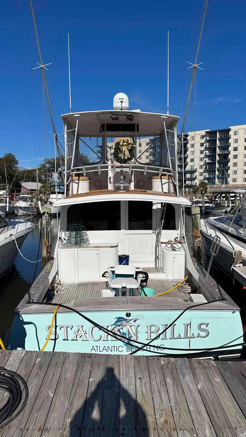 Slide: The Image of 1979 Buddy Davis 46 Convertible boat docked, named "Stackin Bills," with clear blue sky background. - 2