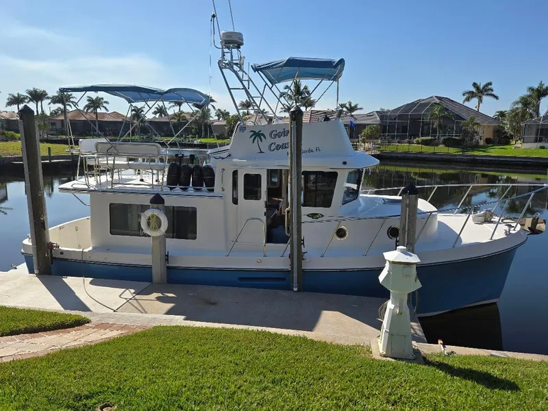 Slide: The Image of 2015 American Tug 365 Flybridge docked by a canal, sunny day, palm trees in background. - 3