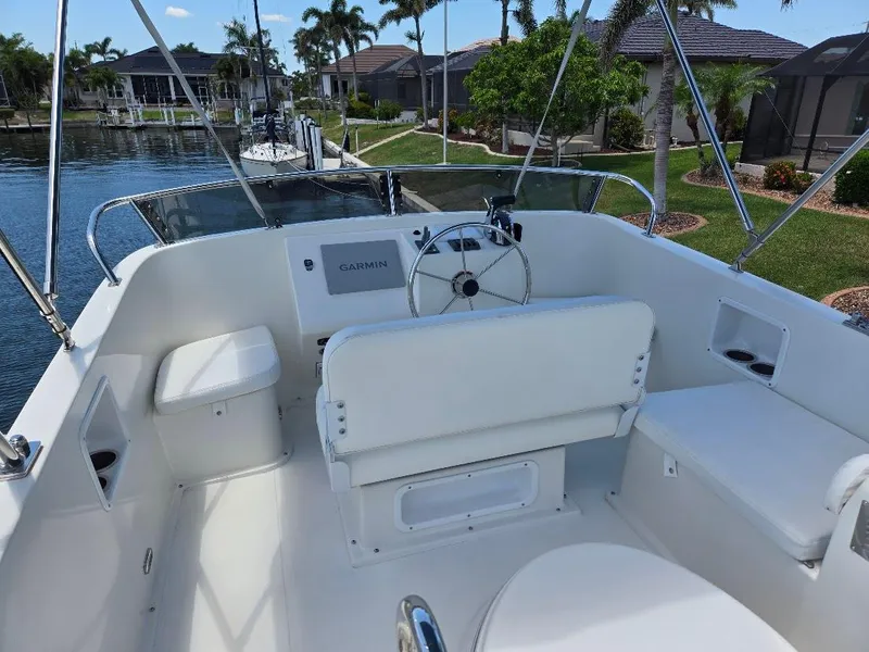 Slide: The Image of Flybridge of 2015 American Tug 365, featuring helm and seating, docked near waterfront homes. - 33