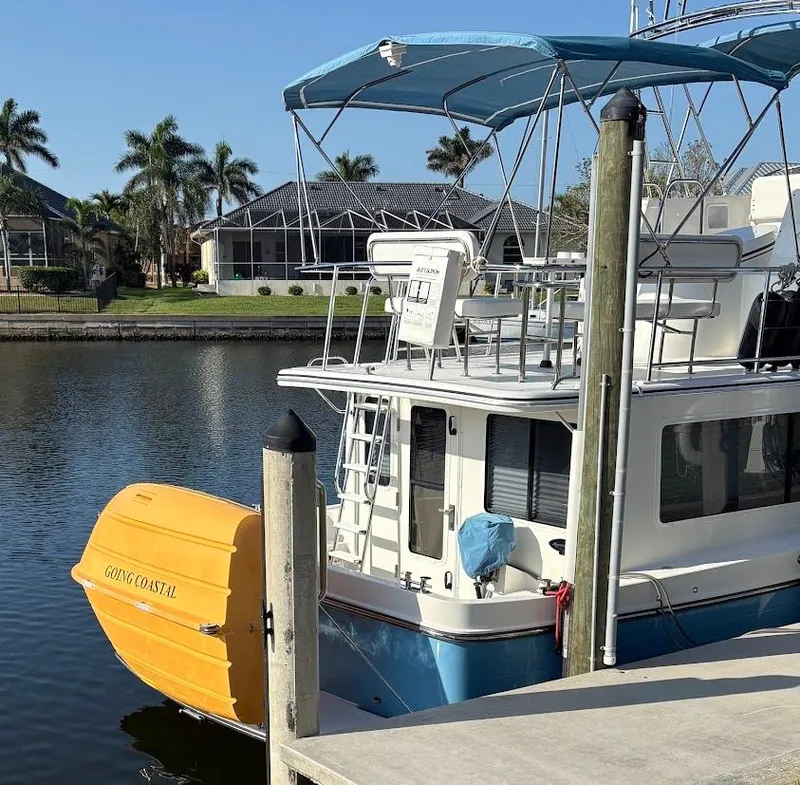 Slide: The Image of 2015 American Tug 365 Flybridge docked by waterfront homes, featuring a yellow dinghy. - 34