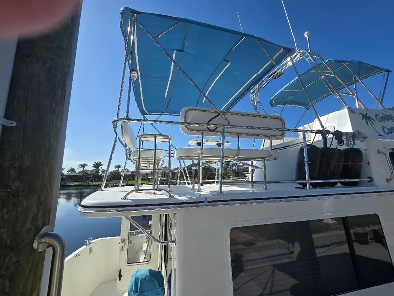 Slide: The Image of 2015 American Tug 365 Flybridge with blue canopy, docked by calm waters. - 5
