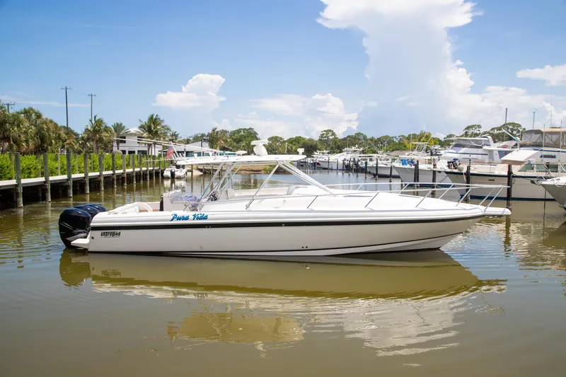 Slide: The Image of 2006 Intrepid 377 WA boat docked on calm water, surrounded by palm trees. - 1