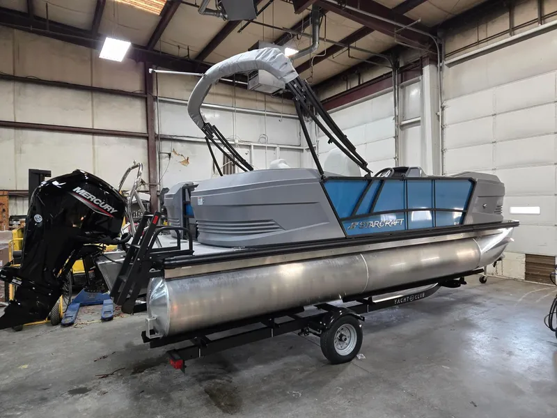 Slide: The Image of 2025 Starcraft GX20R pontoon boat in a warehouse, featuring a Mercury outboard motor. - 5