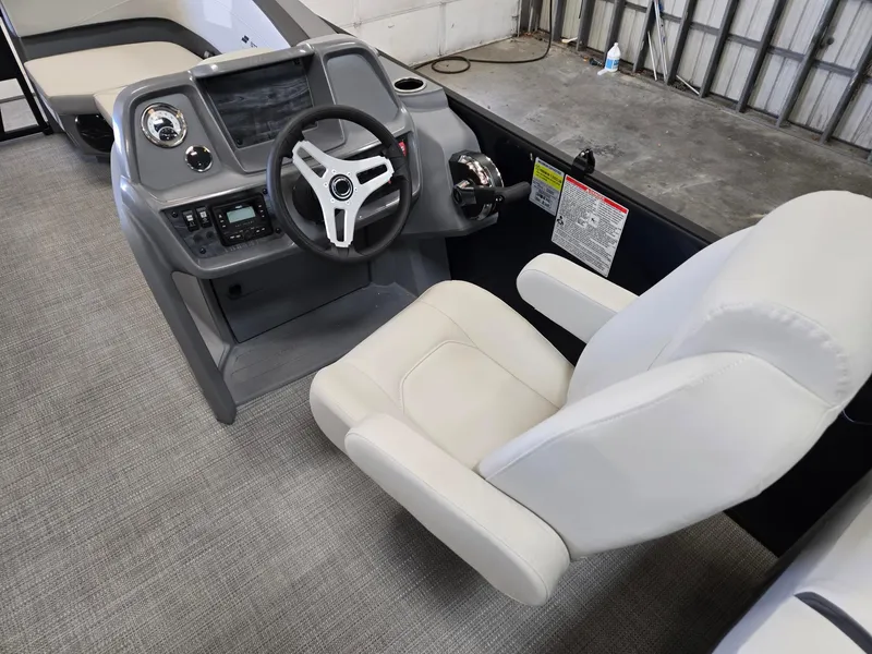 Slide: The Image of 2025 Starcraft GX22R boat cockpit with steering wheel and white captain's chair. - 7