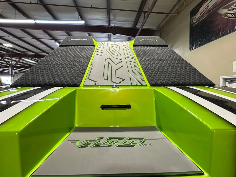 Slide: The Image of 2025 Velocity 40 RAPTOR boat with vibrant green and black design in a showroom. - 6