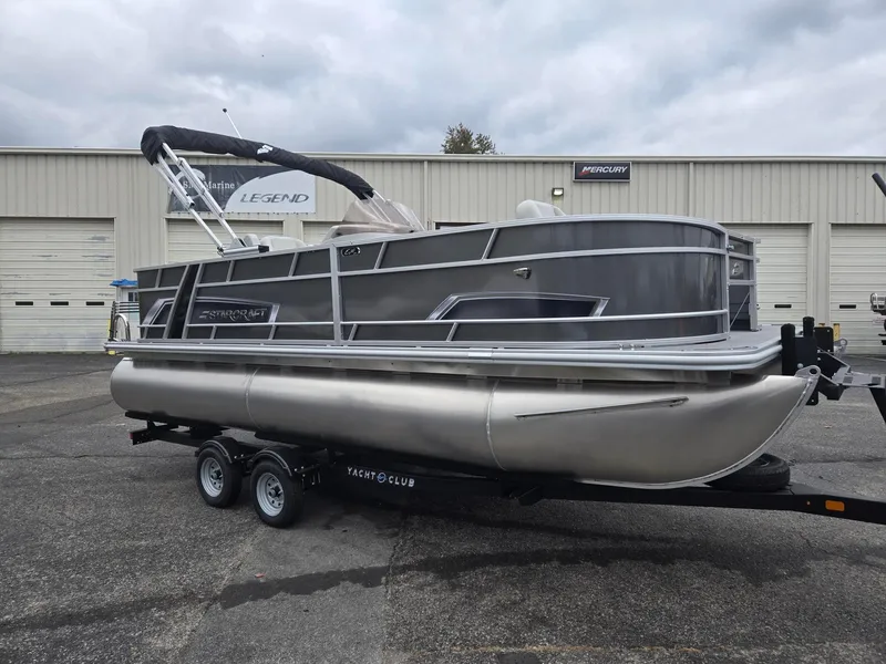 Slide: The Image of 2025 Starcraft EX20FD4 pontoon boat on trailer, parked outside a marine dealership. - 5