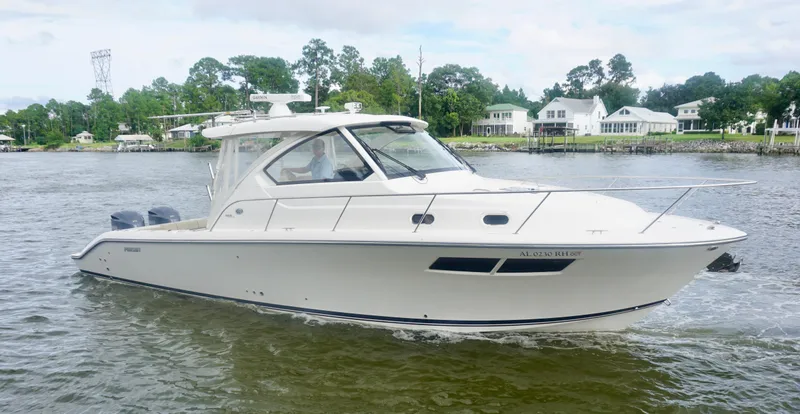 Slide: The Image of 2018 Pursuit OS 355 Offshore boat cruising on a calm river near waterfront homes. - 2