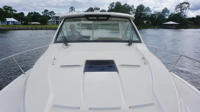 Slide: The Image of 2018 Pursuit OS 355 Offshore boat on water, front view with cabin and windshield. - 6