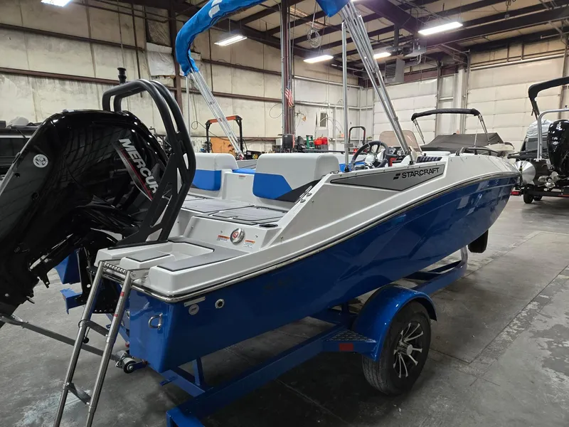 Slide: The Image of 2025 Starcraft SV16OB boat in warehouse, blue hull, Mercury engine, on trailer. - 2