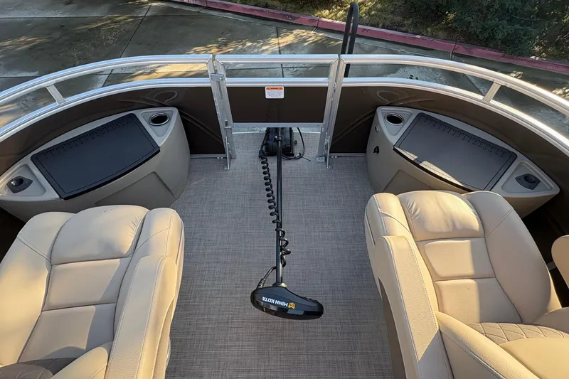 Slide: The Image of 2025 Sun Tracker Sportfish 24 XP3 interior with beige seating and fishing equipment. - 60