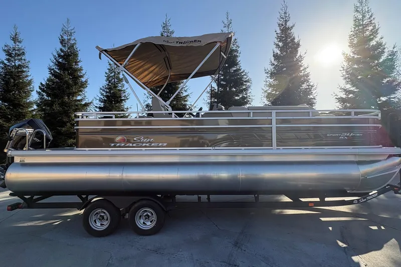 Slide: The Image of 2025 Sun Tracker Sportfish 24 XP3 pontoon boat with canopy, parked on trailer. - 62