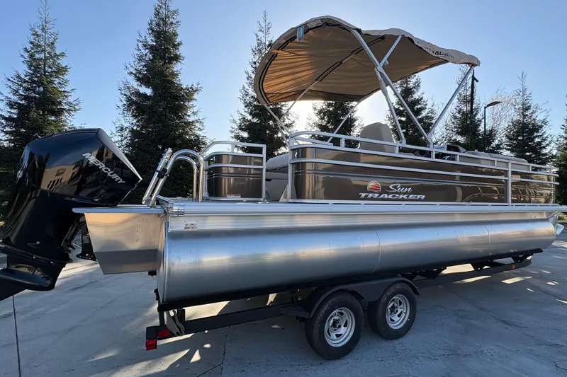 Slide: The Image of 2025 Sun Tracker Sportfish 24 XP3 pontoon boat on trailer, featuring Mercury outboard motor. - 64