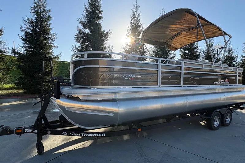 Slide: The Image of 2025 Sun Tracker Sportfish 24 XP3 pontoon boat on trailer, parked outdoors. - 67