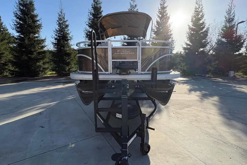 Slide: The Image of 2025 Sun Tracker Sportfish 24 XP3 pontoon boat on trailer, parked outdoors. - 68