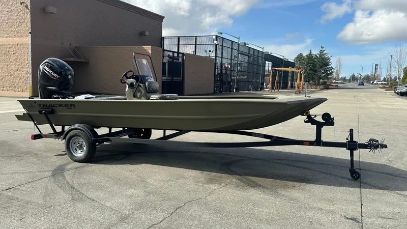 Slide: The Image of 2025 Tracker Grizzly 1860 CC boat on trailer, parked outdoors under a cloudy sky. - 2