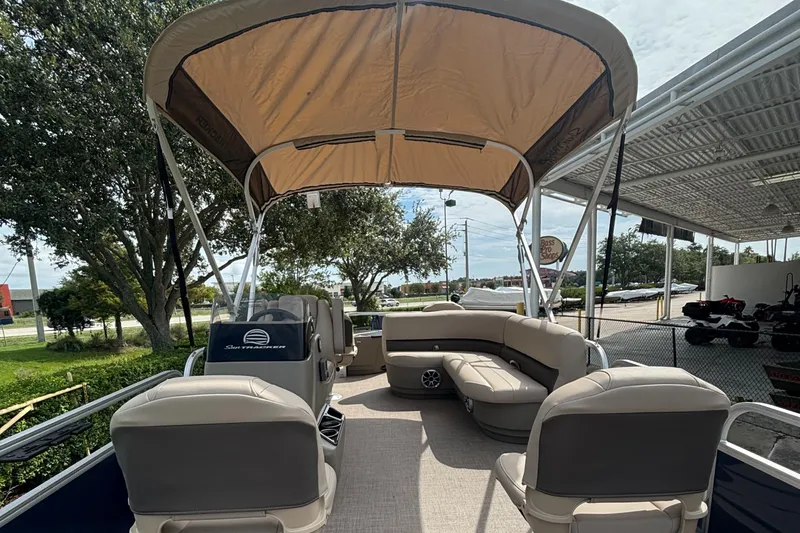 Slide: The Image of 2025 Sun Tracker Bass Buggy 18 DLX pontoon boat with canopy and seating, parked outdoors. - 3