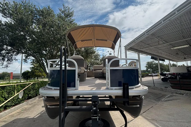 Slide: The Image of 2025 Sun Tracker Bass Buggy 18 DLX pontoon boat with canopy, parked outdoors. - 4