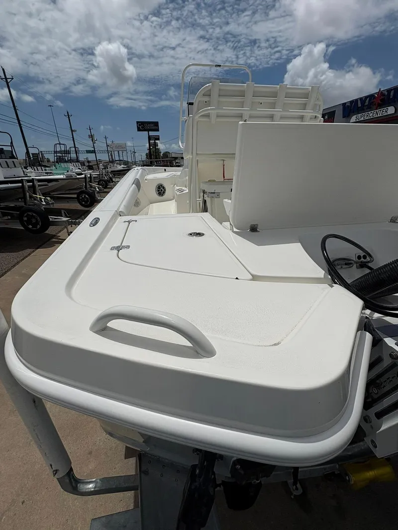 Slide: The Image of 2025 Mako 24 APEX boat deck with storage compartments under a partly cloudy sky. - 10