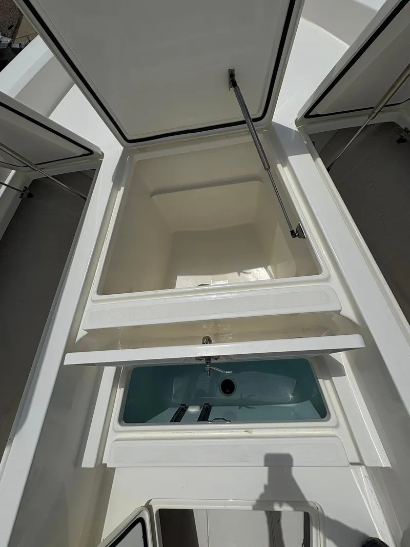 Slide: The Image of Open storage compartments on a 2025 Mako 24 APEX boat, showcasing interior space. - 15