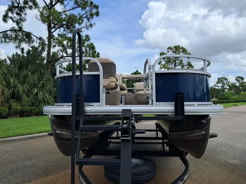 Slide: The Image of 2025 Sun Tracker Bass Buggy 18 DLX pontoon boat on trailer, parked outdoors. - 3