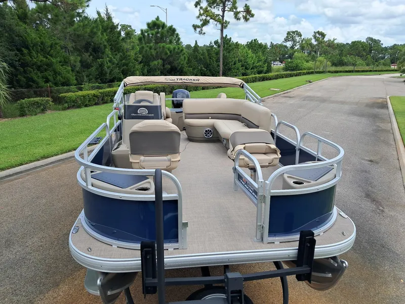 Slide: The Image of 2025 Sun Tracker Bass Buggy 18 DLX pontoon boat on a road, surrounded by greenery. - 4