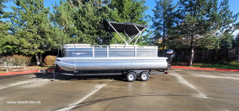 The Image of 2025 Sun Tracker Party Barge 22 RF DLX pontoon boat on trailer, parked outdoors. - 0