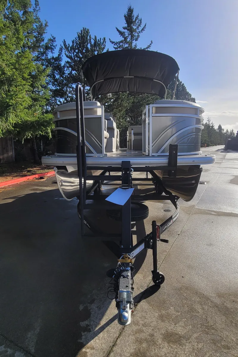 Slide: The Image of 2025 Sun Tracker Party Barge 22 RF DLX pontoon boat on trailer, parked outdoors. - 2