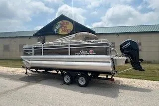 The Image of 2025 Sun Tracker SportFish 20 DLX pontoon boat on trailer, parked outdoors. - 0