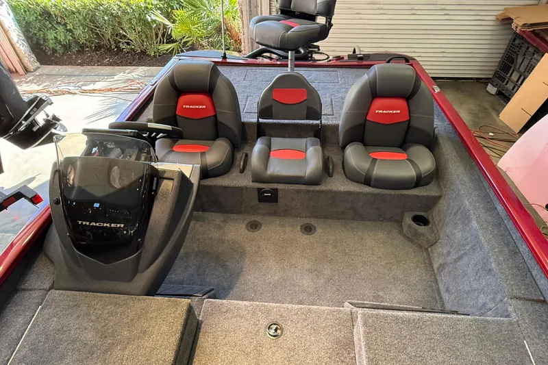 Slide: The Image of 2025 Tracker Savage 215 boat interior with gray and red seating, steering console, and carpeted flooring. - 4
