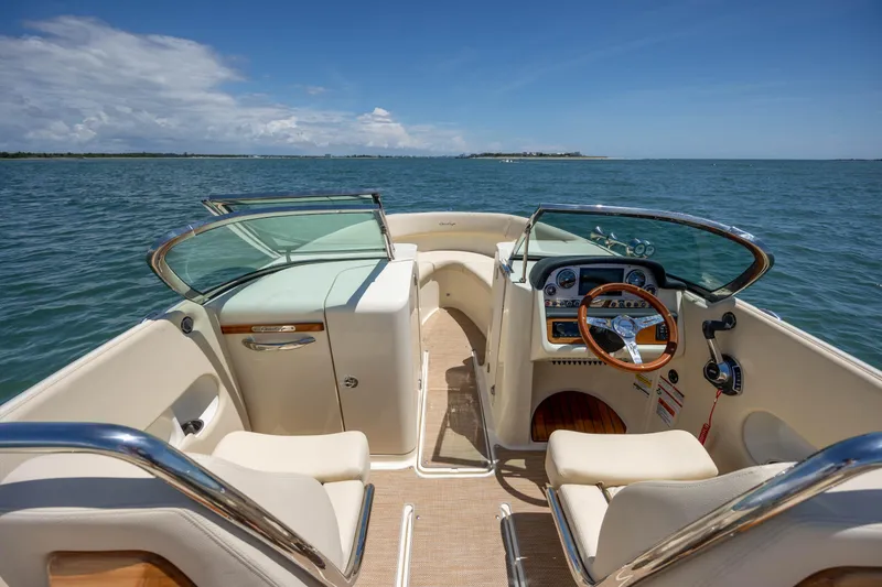 Slide: The Image of 2022 Chris-Craft Launch 27 boat interior with steering wheel, dashboard, and seating on open water. - 13