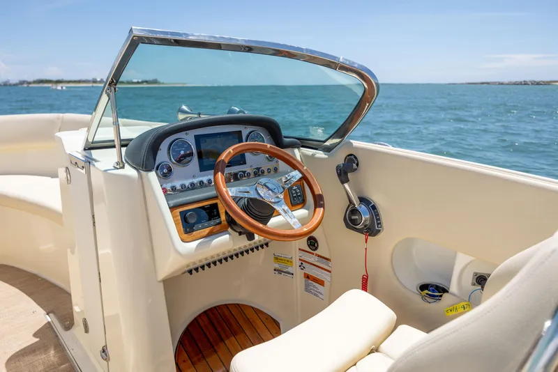 Slide: The Image of 2022 Chris-Craft Launch 27 boat dashboard with wooden steering wheel, on open water. - 15