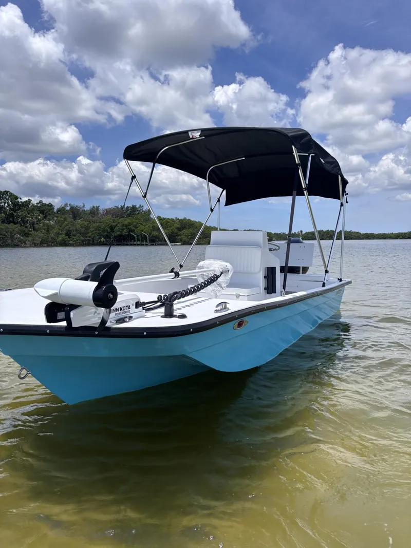 Slide: The Image of 2025 Rabco Buccaneer boat with canopy on calm water under blue sky. - 10