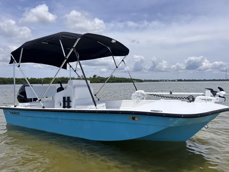 Slide: The Image of 2025 Rabco Buccaneer boat with canopy on calm water under cloudy sky. - 7