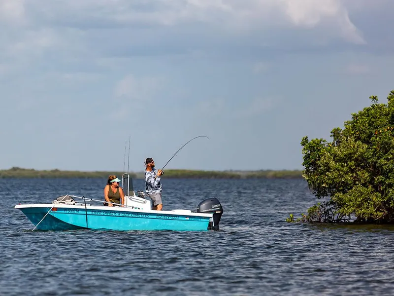 Slide: The Image of Two people fishing on a 2025 Rabco Buccaneer boat in a serene lake. - 9