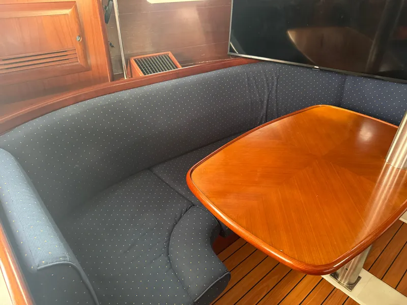 Slide: The Image of Interior of 2005 Beneteau Oceanis Clipper 373 with wooden table and blue cushioned seating. - 17