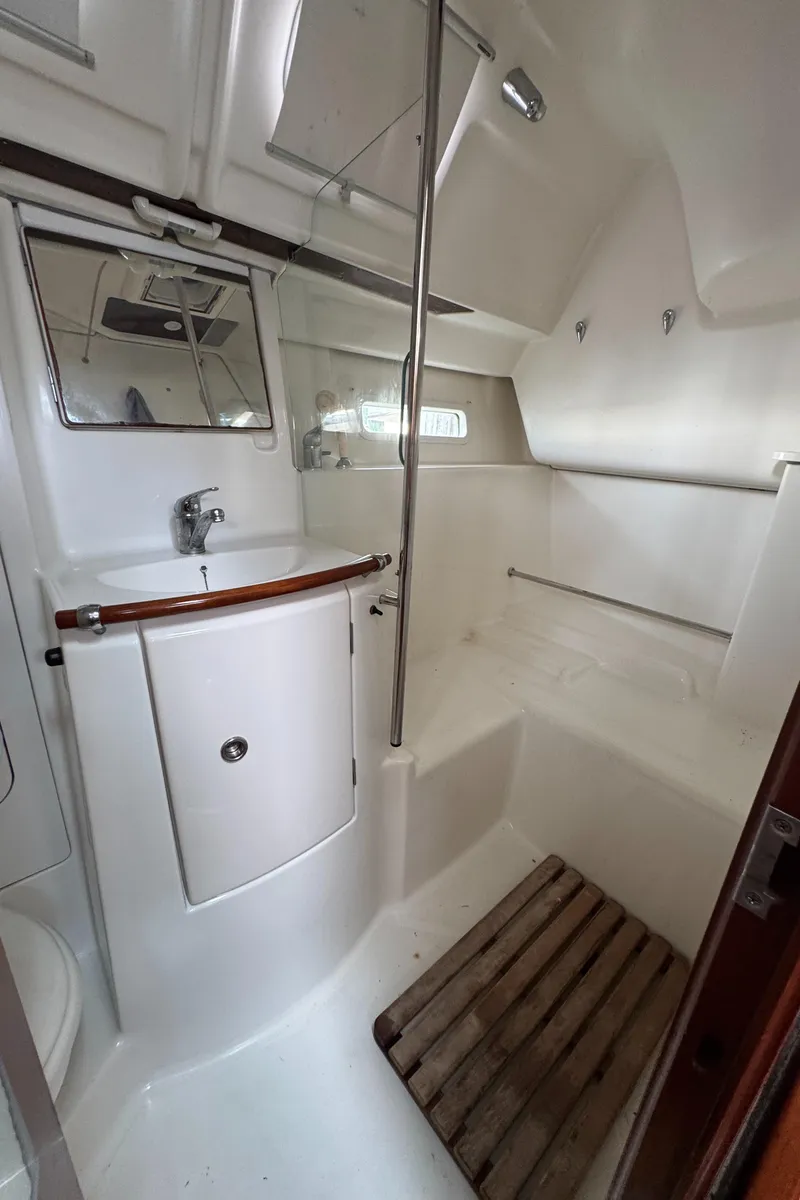 Slide: The Image of 2005 Beneteau Oceanis Clipper 373 bathroom with sink, mirror, and wooden floor mat. - 25