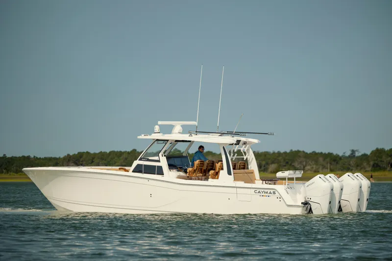 The Image of 2025 Caymas 44 CT boat cruising on a calm lake with multiple outboard engines. - 0