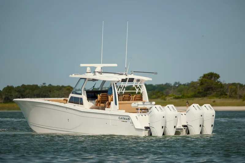 Slide: The Image of 2025 Caymas 44 CT boat with four engines cruising on a calm lake. - 1