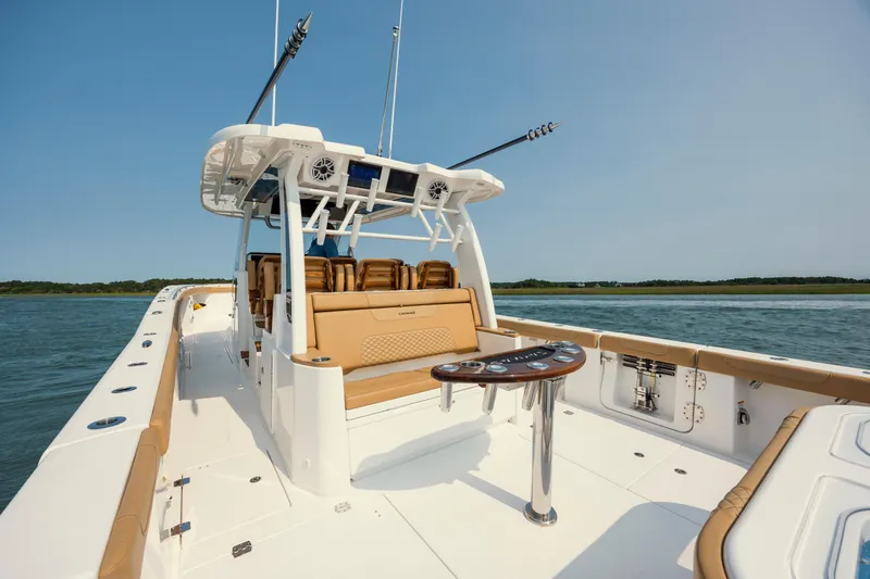 Slide: The Image of 2025 Caymas 44 CT boat with luxurious seating and fishing rods on a calm water backdrop. - 16