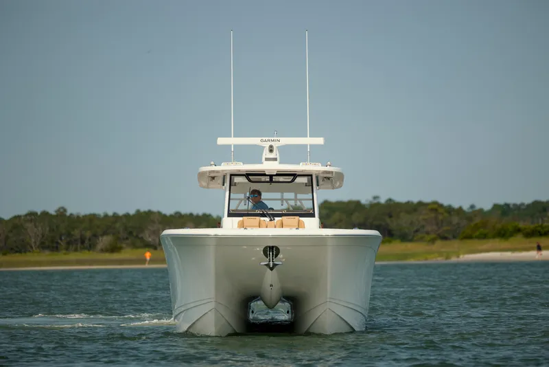 Slide: The Image of 2025 Caymas 44 CT boat cruising on a calm lake with forested shoreline. - 3