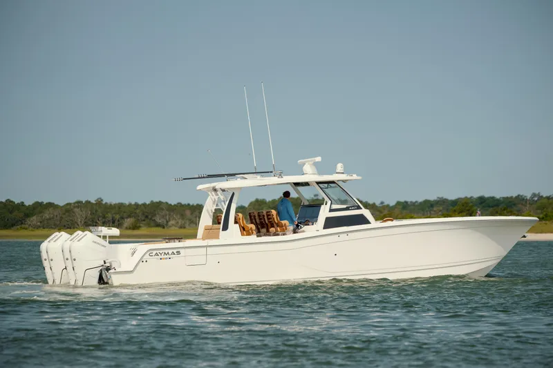 Slide: The Image of 2025 Caymas 44 CT boat cruising on a calm lake with scenic background. - 6
