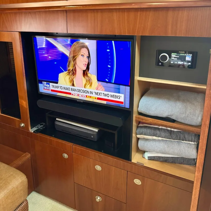 Slide: The Image of Entertainment area inside 2006 Sea Ray 48 Sundancer yacht with TV and storage shelves. - 22