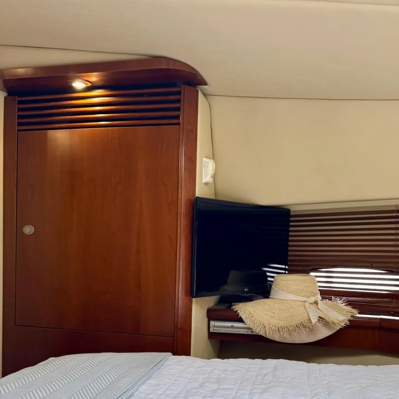 Slide: The Image of Interior of 2006 Sea Ray 48 Sundancer with wooden cabinetry, TV, and sun hat on bed. - 26