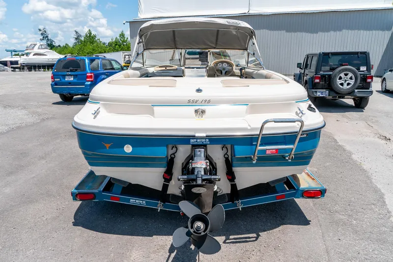 Slide: The Image of 1995 Glastron 195 SSV boat on trailer, parked outdoors with vehicles in background. - 11