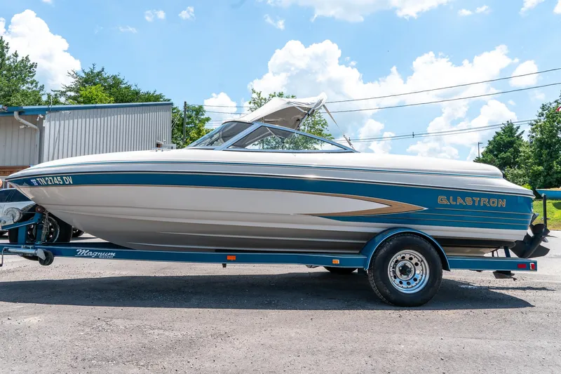 Slide: The Image of 1995 Glastron 195 SSV boat on trailer, parked outdoors under a blue sky. - 7